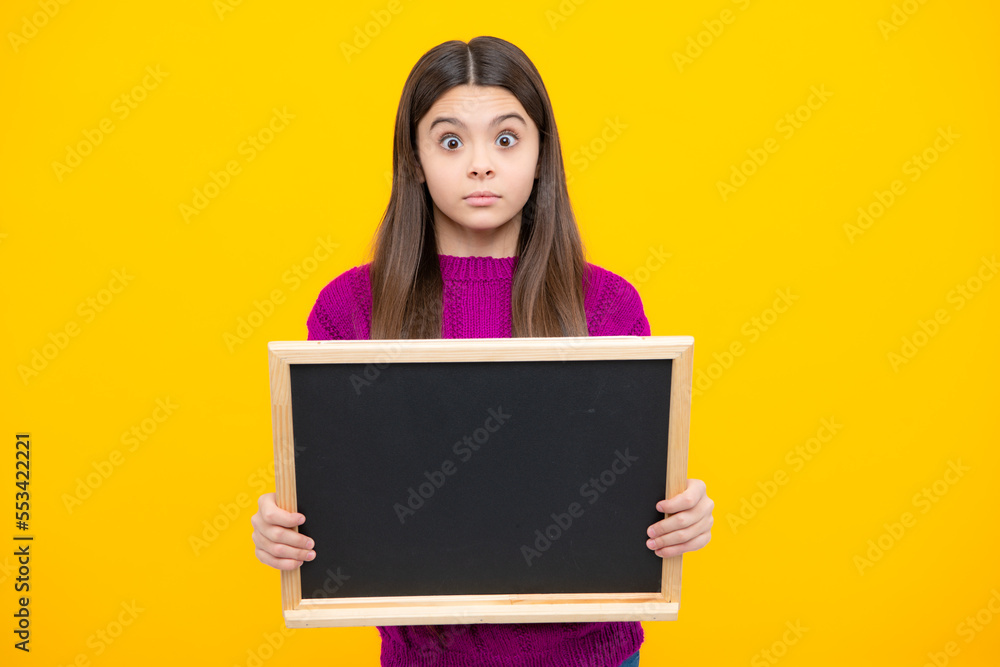 School sales board. Cheerful teenage girl kid hold blackboard chalkboard with copy space on yellow background. Surprised emotions of young teenager girl.