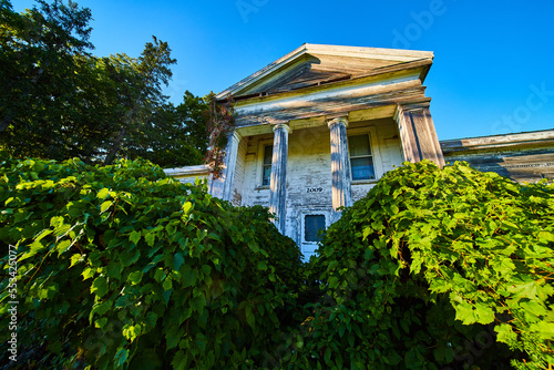 American townhouse mansion abandoned in woods with large white pillars