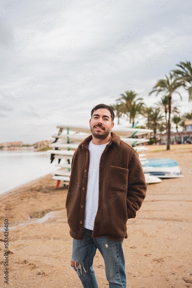 Caucasian young man by the lake in cloudy weather wearing winter clothing