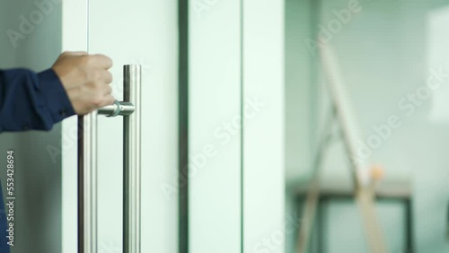 Close up hand of successful businessman open the glass office entrance in the modern business centre Confident employee man walking through the door entering meeting room indoors Business life concept photo