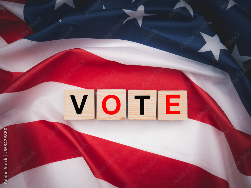 Fototapeta premium Wooden cubes with letters VOTE over the American flag background
