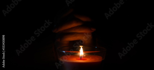 a woman warms her hands on a burning candle
