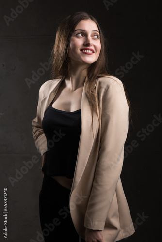 Portrait of a young brunette with long hair in the studio. Dramatic photo in dark colors.