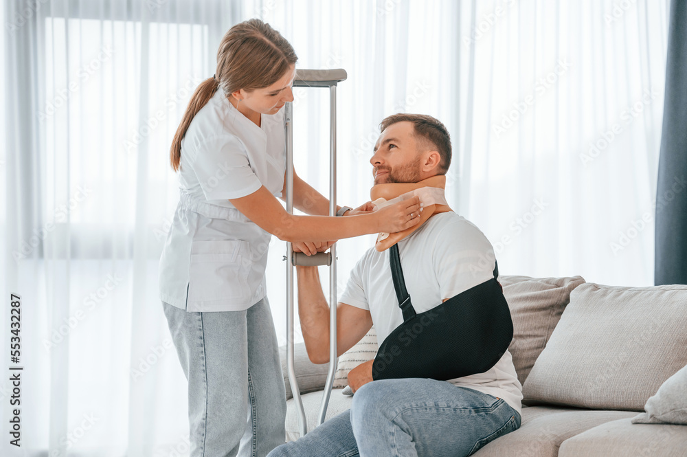 Fototapeta premium Nurse is helping injured man at home