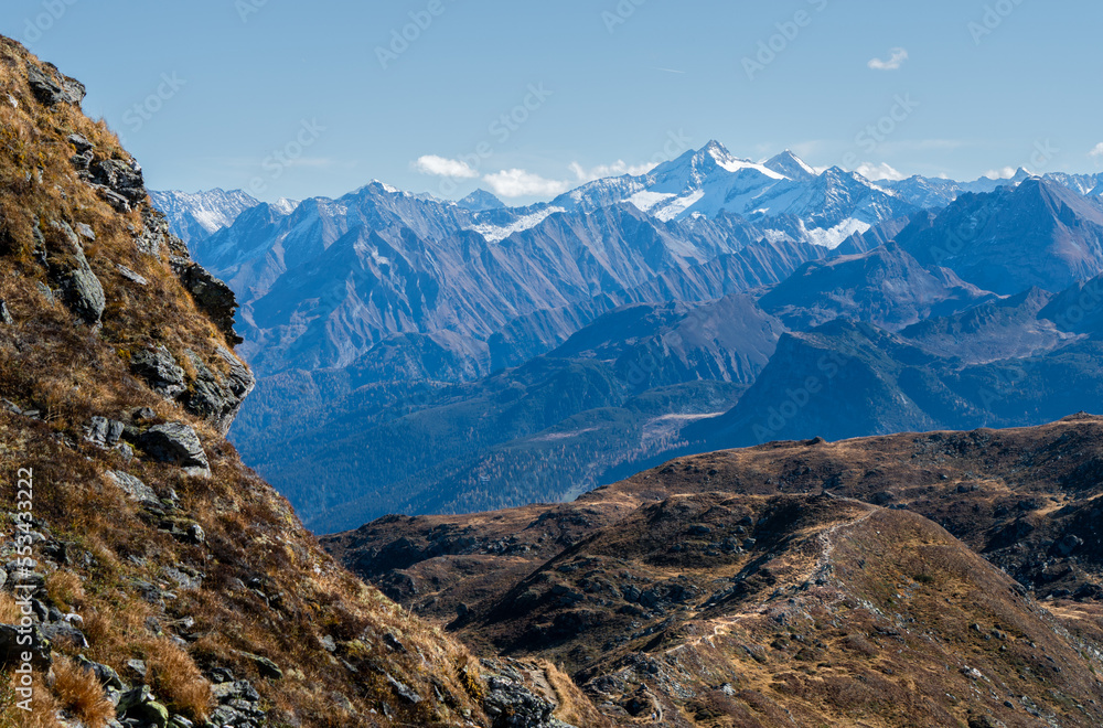 Reichenspitze and Kuchelmooskopf peaks covered in snow and ice on a beautiful sunny day of autumn in Austrian Alps. Dramatic cliffs of Alpine moutains with autumn colored meadows in front.