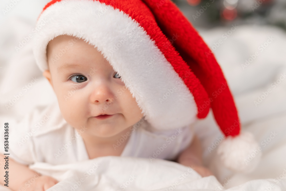 cute baby in Santa hat at home in bed. The first New Year. Christmas Gift cute baby in Santa hat at home in bed. The first New Year. Christmas Gift