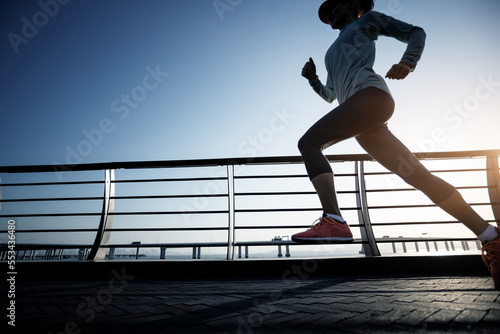 Fitness woman runner running on seaside bridge