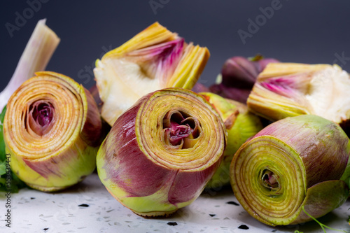 Heads of raw fresh purple romanesco artichoke vegetable and pilled hearts
