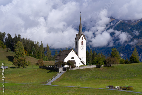 Protestant church of mountain village Versam, Canton Graubünden, on a hill with trees and surrounding wall at autumn day. Photo taken September 26th, 2022, Versam, Safiental, Switzerland.