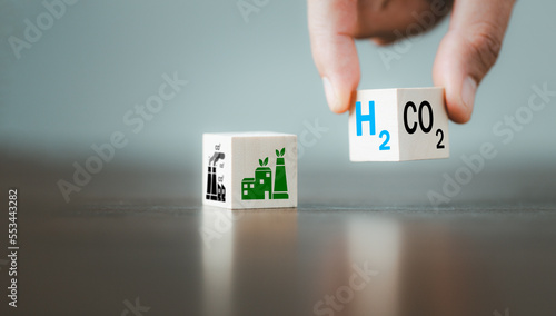 Free Carbon, alternative energy and global climate change concepts. Hand flipping wooden cube blocks with CO2 Carbon dioxide, change to H2 Hydrogen text on table background. Sustainable car energy.