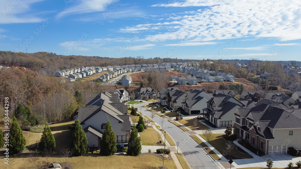Fototapeta premium Aerial view rare beautiful cloud formation over subdivision sprawl with row of two story houses lead to horizontal suburbs Atlanta, Georgia, USA