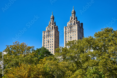 Towering New York City building in Central Park behind lush green trees