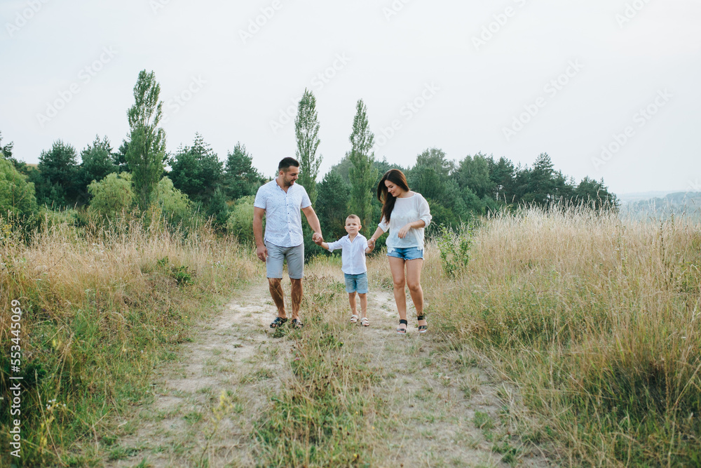 Happy young family father, mother and little son having fun outdoors, playing together in park Happy young family father, mother and little son having fun outdoors, playing together in park