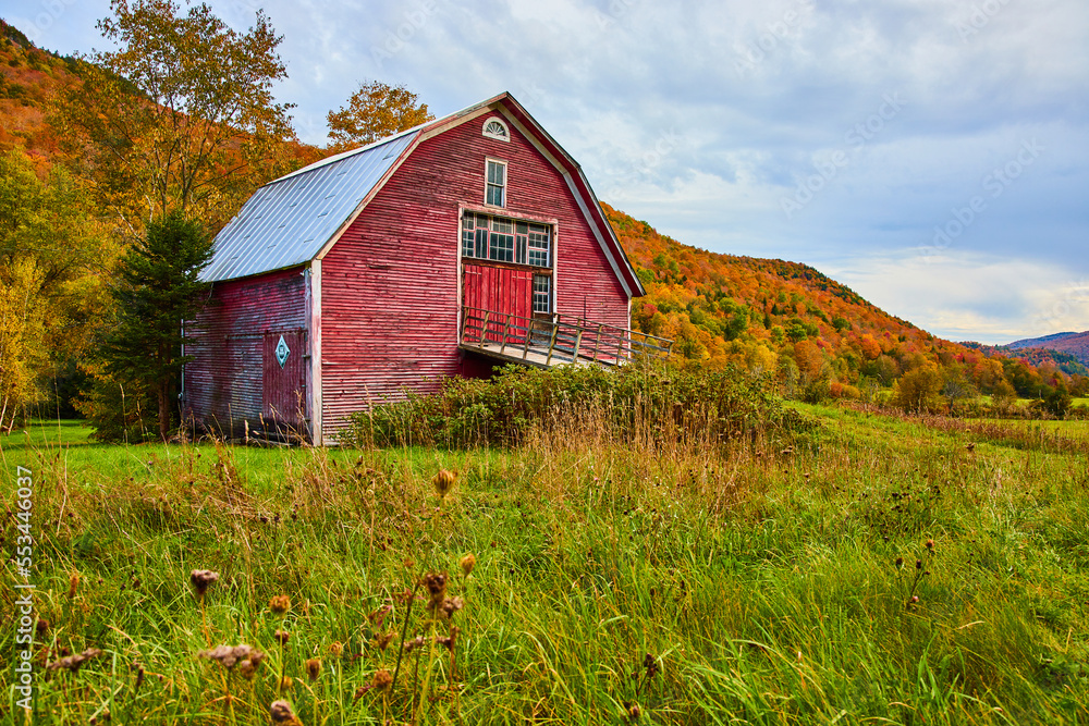Red barn in country fields surrounded by mountains of peak fall foliage ...