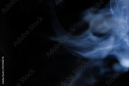Graceful swirls of blue incense smoke isolated from black background. Close-up of vapor. Soft focus and texture from vintage Helios 44m-4 lens. Abstract graphic design asset. Horizontal copy space.
