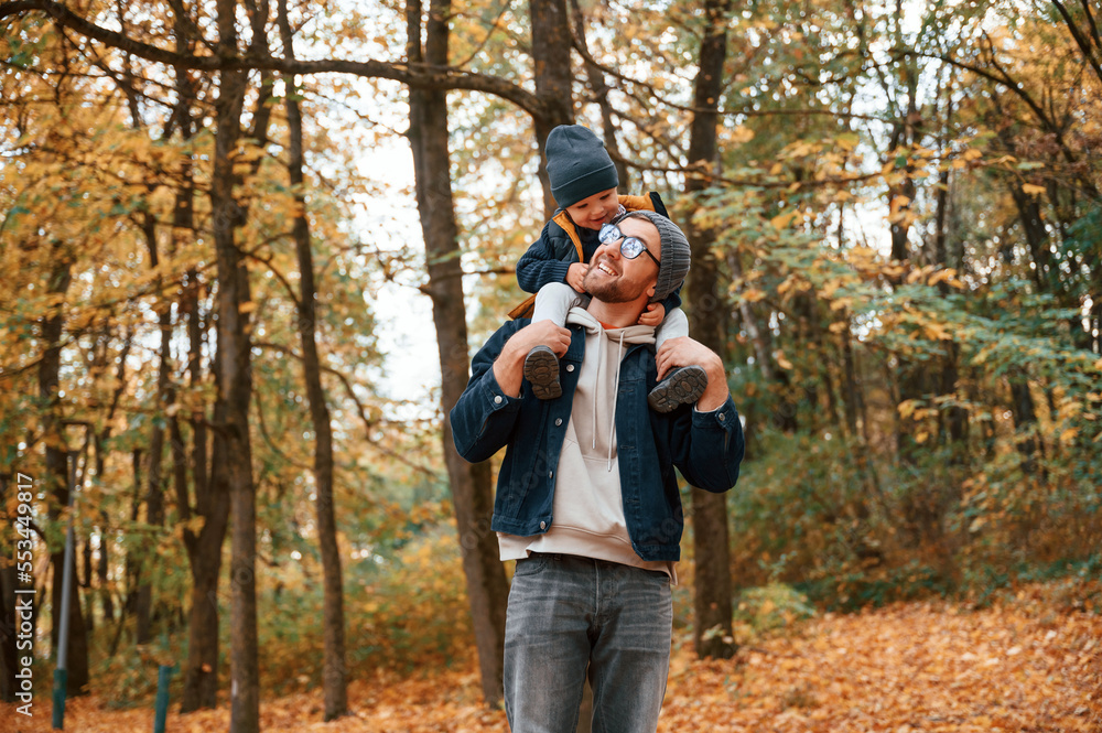 Having a walk in forest. Father and young son is together outdoors at daytime Having a walk in forest. Father and young son is together outdoors at daytime