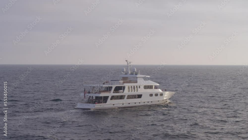Arcing drone shot of a luxury yacht sailing through the open ocean Arcing drone shot of a luxury yacht sailing through the open ocean