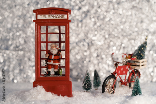 Santa in the telephone box, with Santa's bicycle in the silver wood. Christmas decoration