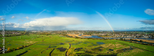 Rainbow at Sunrise over RSPB Exminster and Powderham Marshes from a drone in panorama, Exeter, Devon, England
