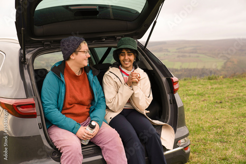 Female friends sitting in car trunk after hiking © Cultura Creative