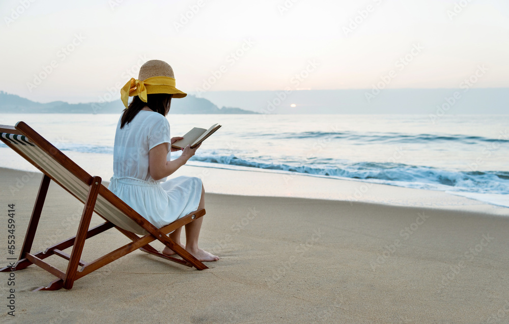 Young lady reading a book on the beach.