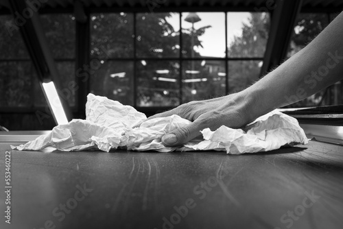 Closeup of hand cleaning a surface with a rag in black and white