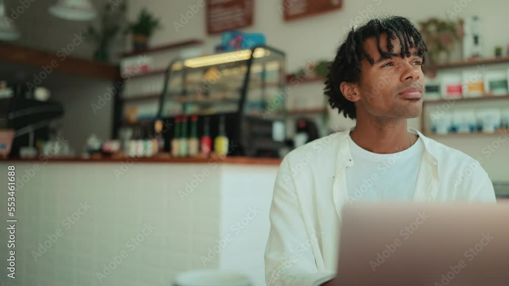 Pensive African man working on laptop and looking around in the cafe Pensive African man working on laptop and looking around in the cafe
