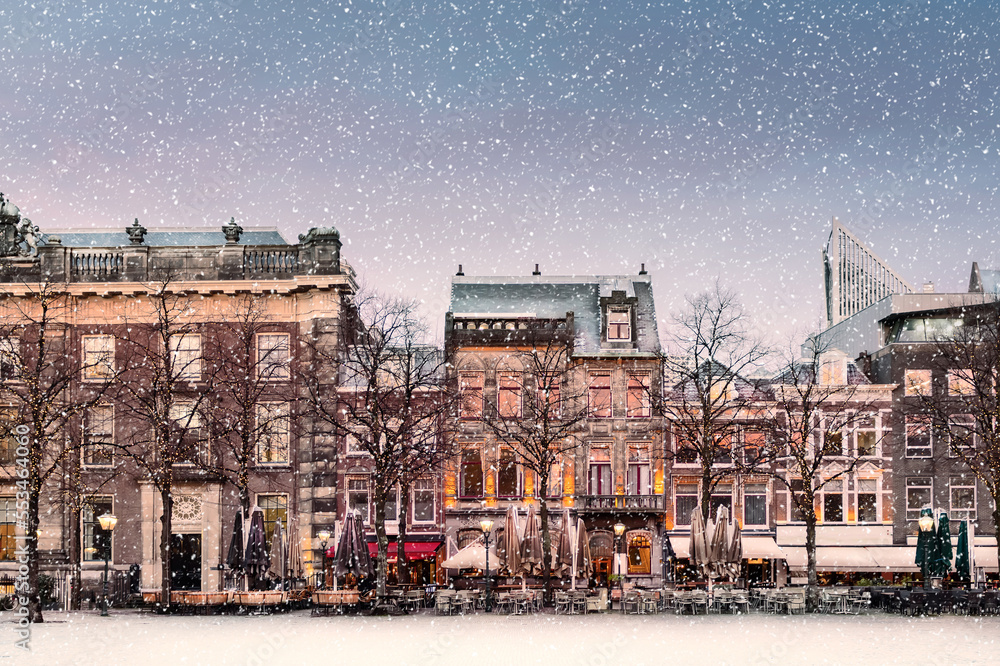Winter view with snowfall of the central historic square Plein next to the Binnenhof with bars and restaurants in the ancient city center of The Hague, The Netherlands