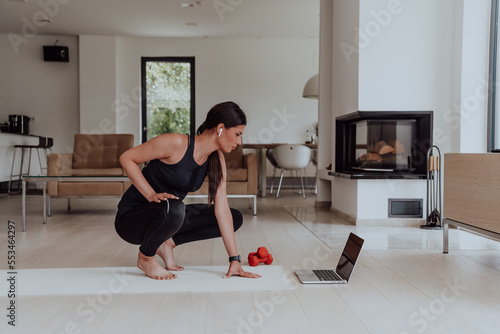 Fototapeta Naklejka Na Ścianę i Meble -  Young Beautiful Female Woman with Trainer via Video Call Conference in Bright Sunny House. Healthy Lifestyle, Wellbeing and Mindfulness Concept.