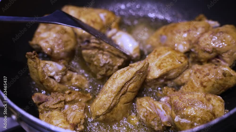 Spicy Chicken Pieces Sizzling In Oil And Being Stirred By Metal Slotted Spatula. Close Up, Slow Motion Spicy Chicken Pieces Sizzling In Oil And Being Stirred By Metal Slotted Spatula. Close Up, Slow Motion