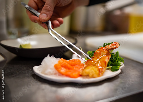 chef cooking slice salmon fish and shrimp with salad on kitchen