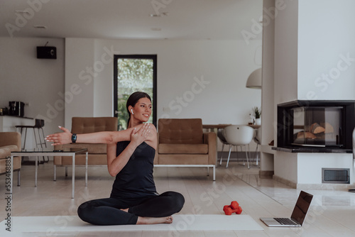 Fototapeta Naklejka Na Ścianę i Meble -  Young Beautiful Female Exercising, Stretching and Practising Yoga with Trainer via Video Call Conference in Bright Sunny House. Healthy Lifestyle, Wellbeing and Mindfulness Concept.