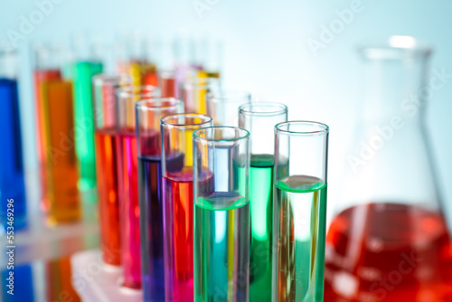 Different laboratory glassware with colorful liquids on turquoise background, closeup