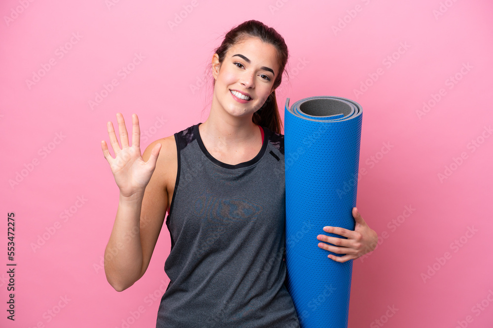 Young Brazilian sport woman going to yoga classes while holding a mat isolated on pink background counting five with fingers Young Brazilian sport woman going to yoga classes while holding a mat isolated on pink background counting five with fingers