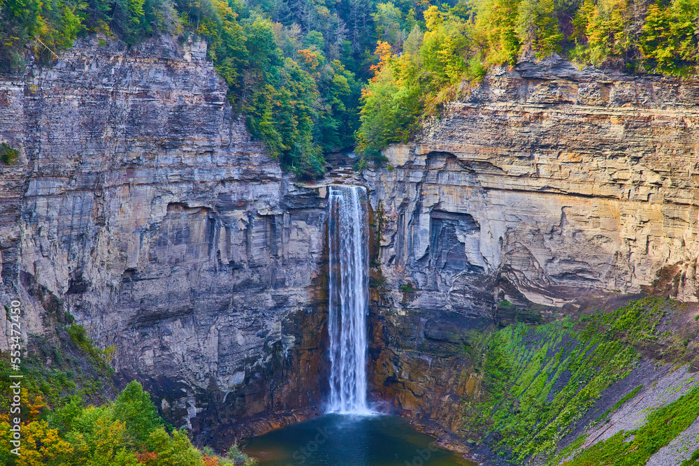Fototapeta premium Huge waterfall flowing into large canyon with rocky cliffs