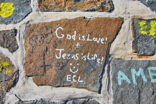 Fotografie, Tablou Detail down on stone wall graffiti God is Love Jesus is Life smiling face