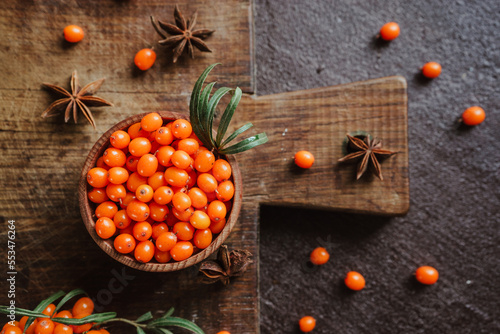 fresh sea buckthorn berries and anise for healing spicy tea on a brown board on a dark background 1
