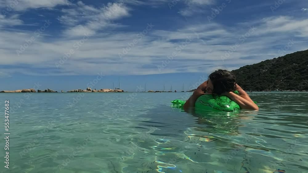 Sea water surface perspective of woman relaxing on inflatable green alligator mattress at Santa Giulia beach in Corsica, France. Slow motion at 50fps Sea water surface perspective of woman relaxing on inflatable green alligator mattress at Santa Giulia beach in Corsica, France. Slow motion at 50fps