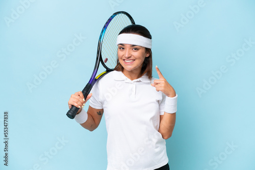 Young tennis player woman isolated on blue background giving a thumbs up gesture © luismolinero