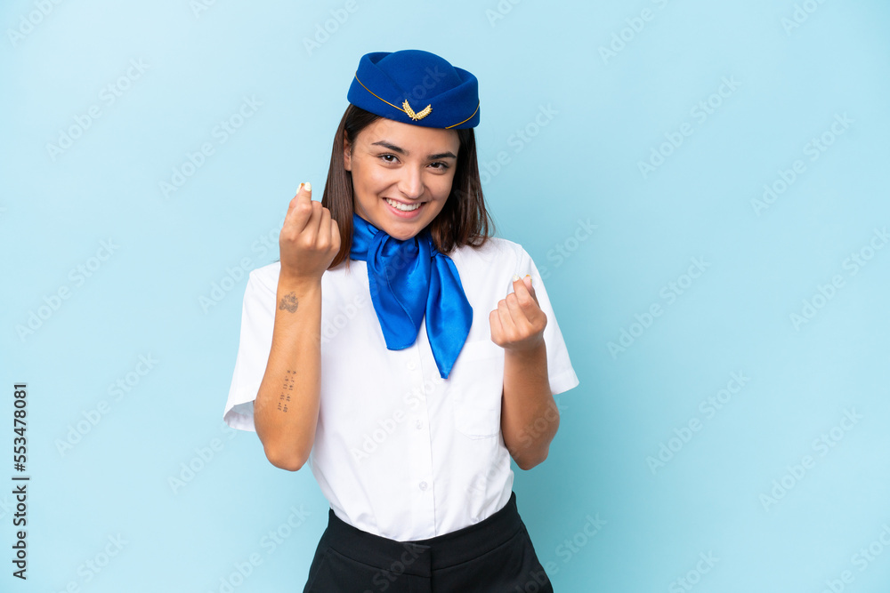 Airplane stewardess caucasian woman isolated on blue background making money gesture Airplane stewardess caucasian woman isolated on blue background making money gesture
