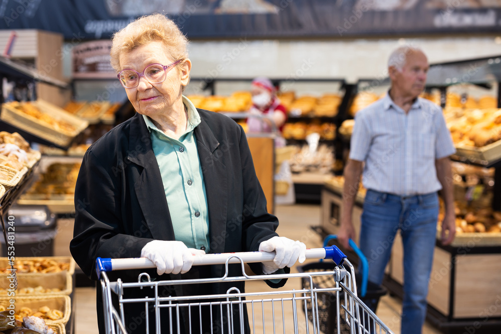 an elderly woman is shopping in the bread department of a supermarket