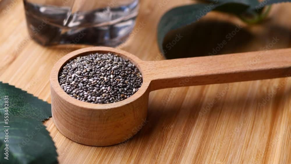 top view of chia seed in a wooden spoon and leaf on table top view of chia seed in a wooden spoon and leaf on table