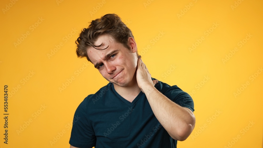 Portrait of young hipster man 20s with sore neck shoulder problem isolated on yellow background in studio Portrait of young hipster man 20s with sore neck shoulder problem isolated on yellow background in studio