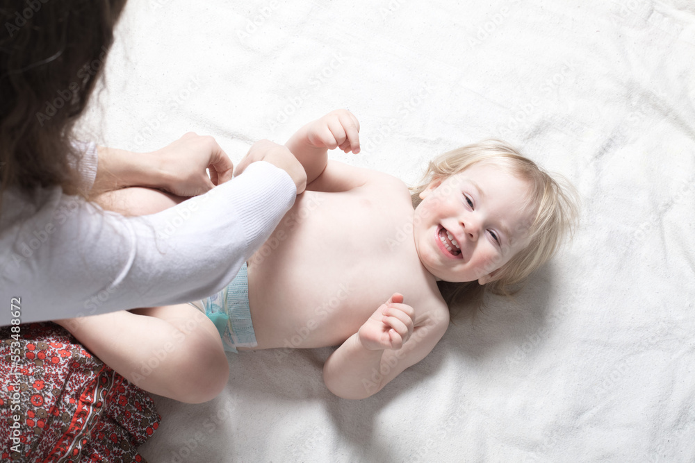 Mom changes diapers for a baby lying on the bed Mom changes diapers for a baby lying on the bed