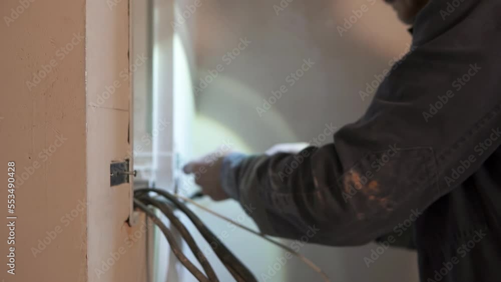 An electrician installs a switchboard in a new building. An electrician installs a switchboard in a new building.