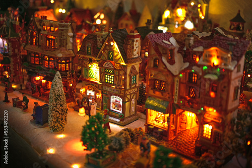 Christmas village with large illuminated houses, shops, tea house, miniature figurines and snow-covered trees