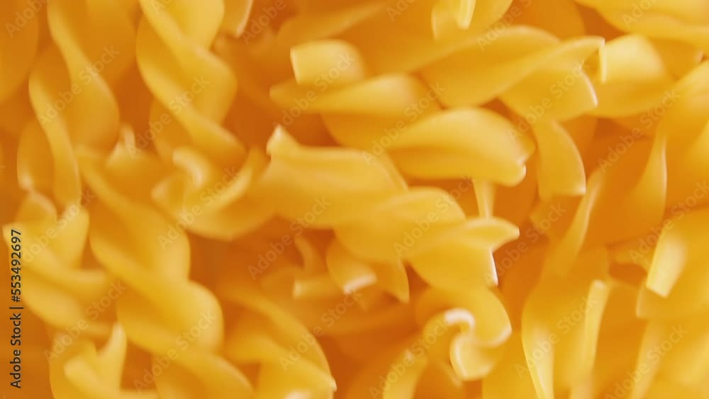 Uncooked Fusilli Pasta - Top View. Fat and Unhealthy Food. Dry Spiral Macaroni, Moving Background. Italian Culture and Cuisine. Raw Golden Pasta Pattern. Downward Movement