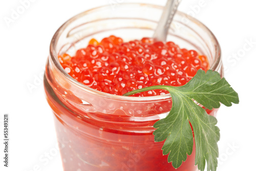 Glass jar and spoon with delicious red caviar and parsley.