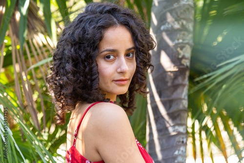 Young woman with curly hair enjoying in a paradise park  