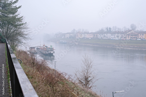 View of the river and city surrounded by fog in winter. Pleasure boat. Pavia. Italy. Lombardy © Viktoryia